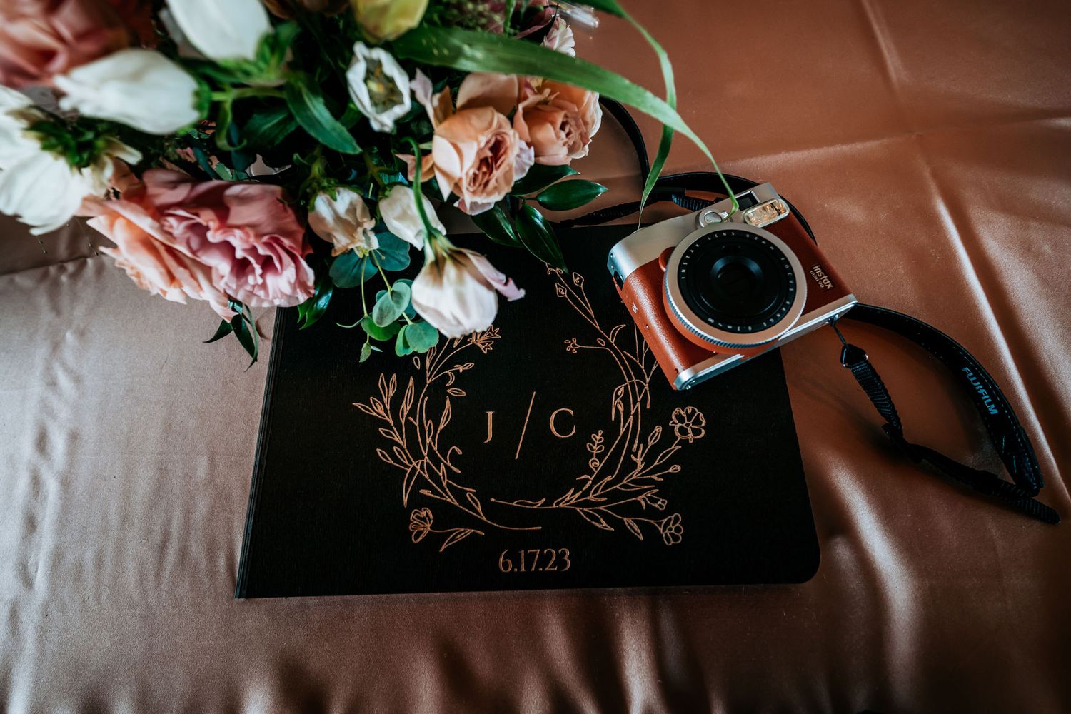 Wedding stationery with floral arrangement and vintage camera on linen tablecloth.