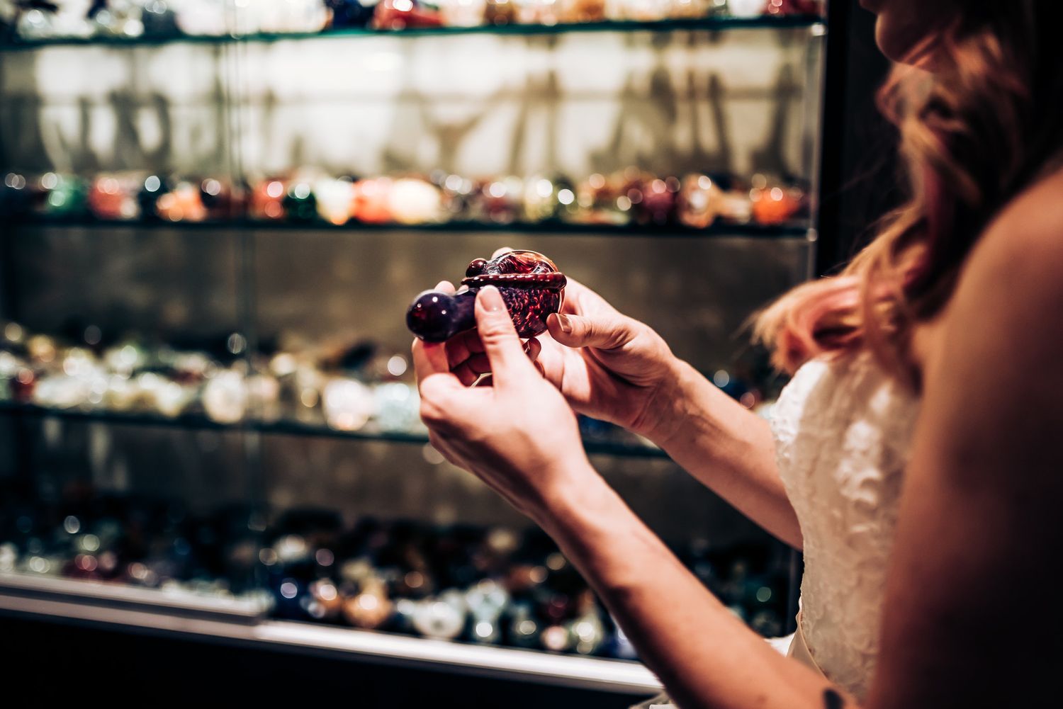 A close-up shot showing hands holding a dark object in front of a jewelry display case.
