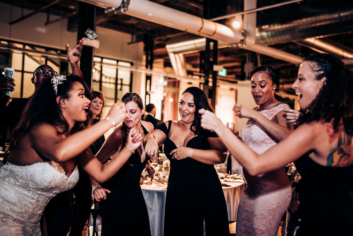 A group of wedding guests and the wedding party celebrate on the dance floor with joyful expressions.