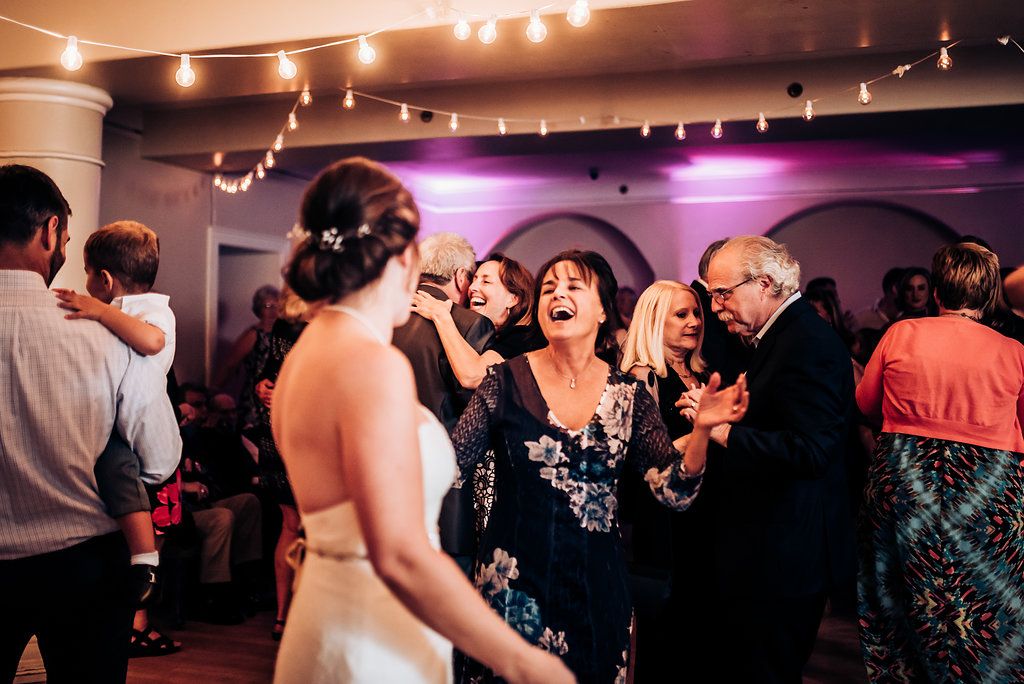 Wedding guests laughing and dancing together during a joyous reception celebration.