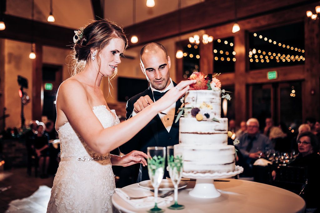 Couple cutting their elegant white wedding cake together at reception.
