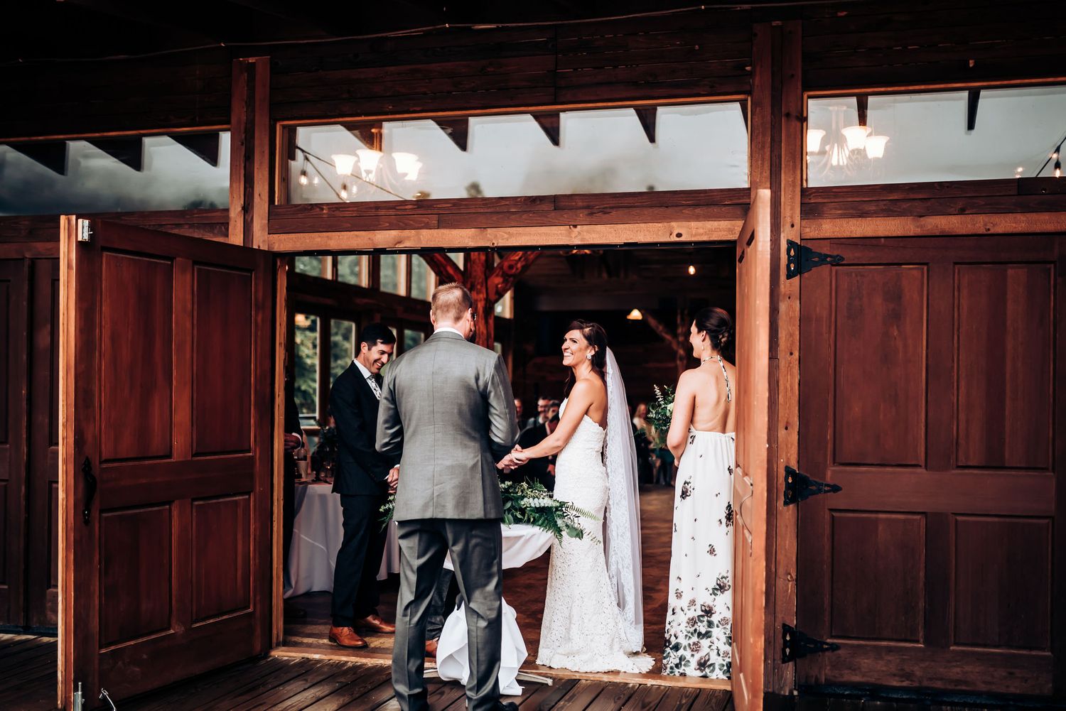 Wedding ceremony in progress inside a rustic wooden structure with sunlight streaming through.