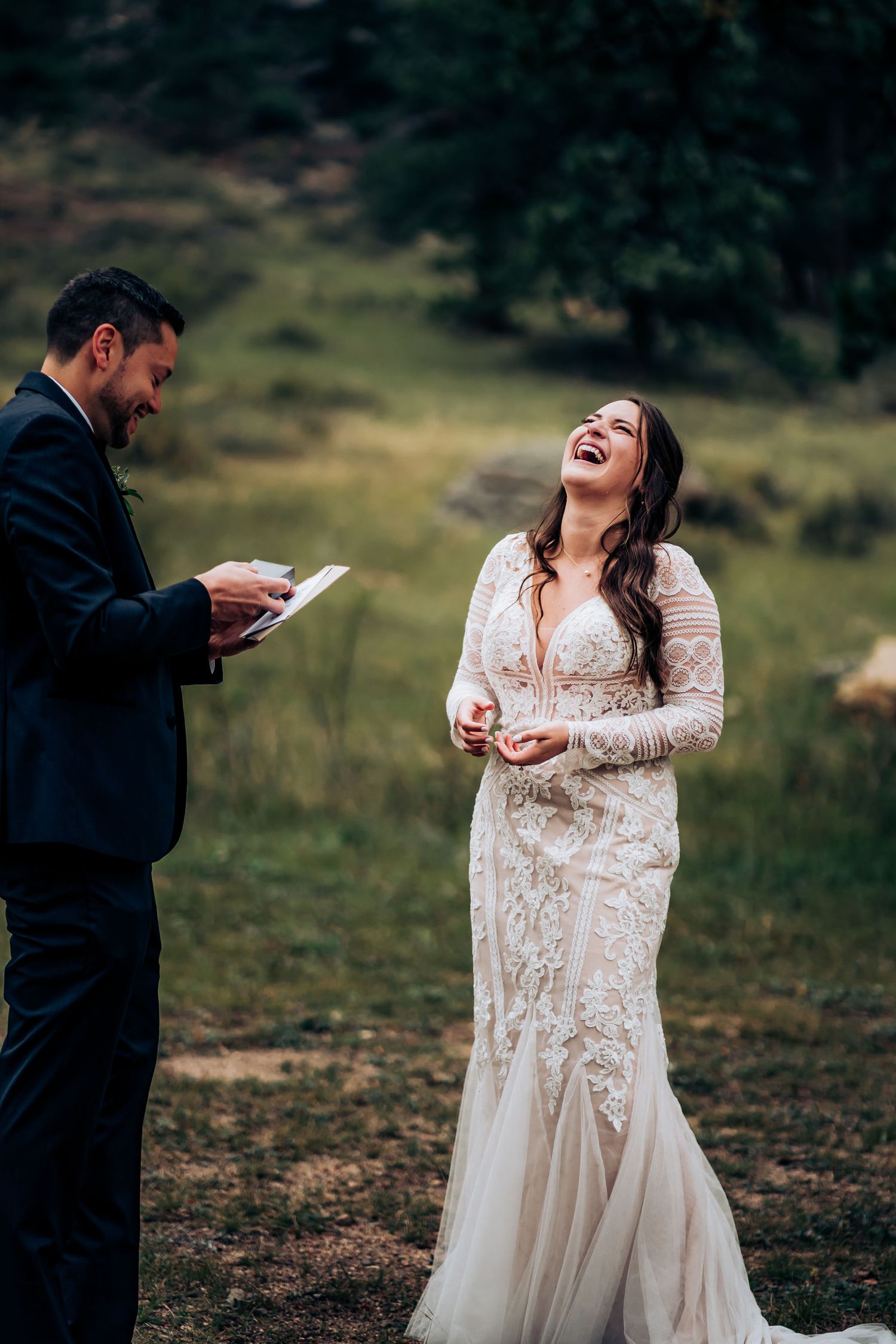 A joyful moment shared between a couple reading vows in an outdoor mountain setting.