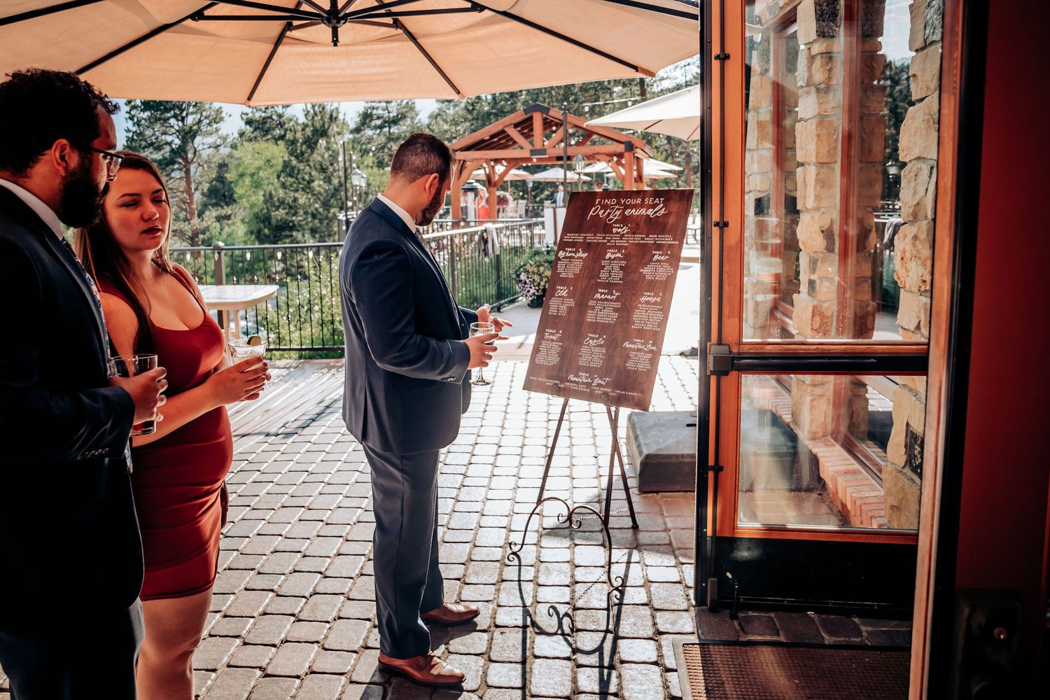 Wedding guests viewing a welcome sign under a beige patio umbrella.