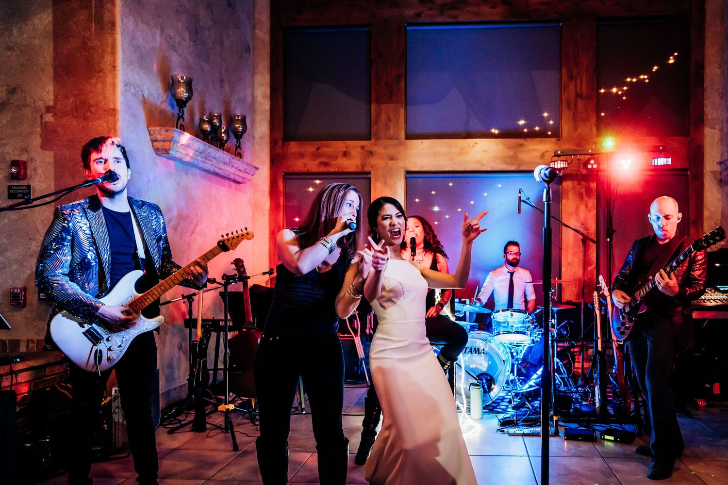Wedding band performing live music with instruments and dramatic stage lighting.