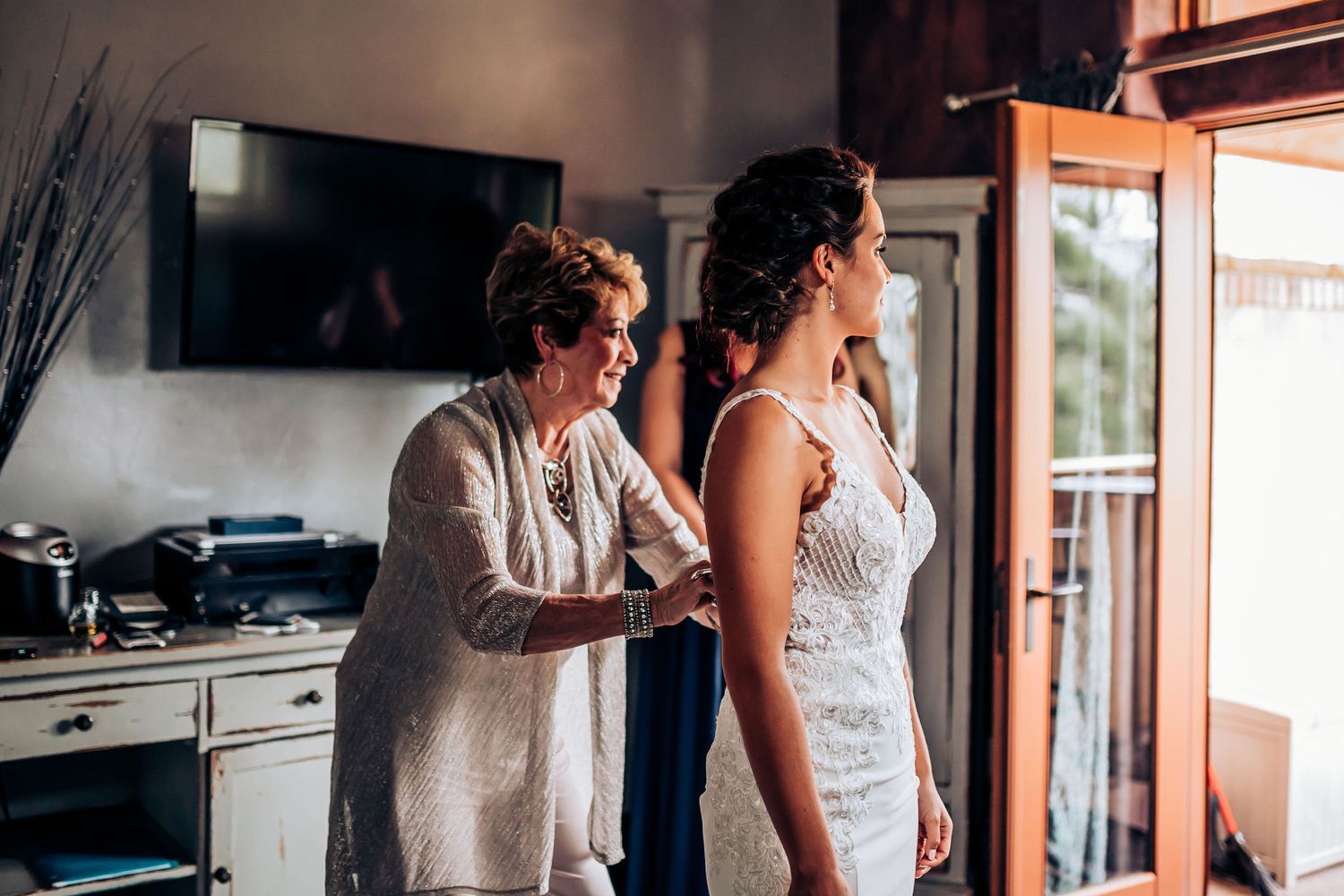 Wedding dress preparation scene with helpers assisting with final touches.