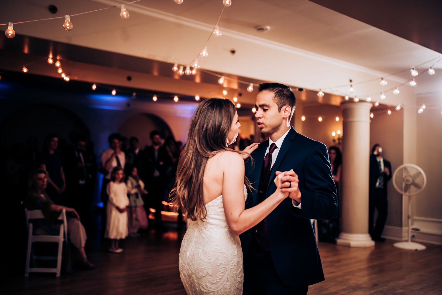 A couple shares an intimate slow dance under warm reception lighting.