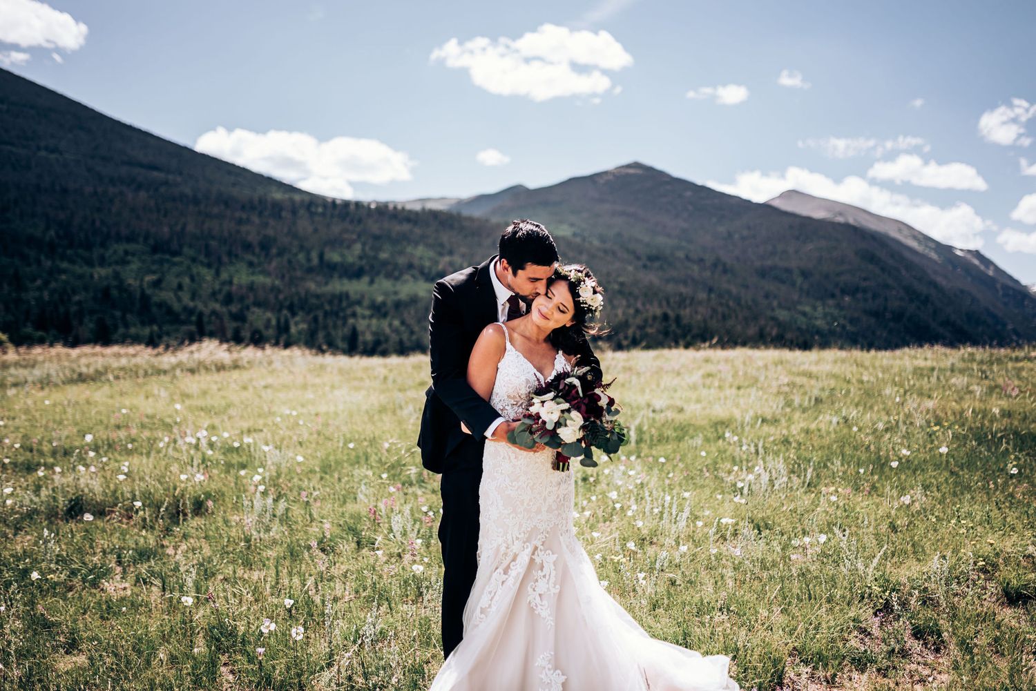 A romantic mountain wedding portrait with dramatic peaks and blue skies as backdrop.