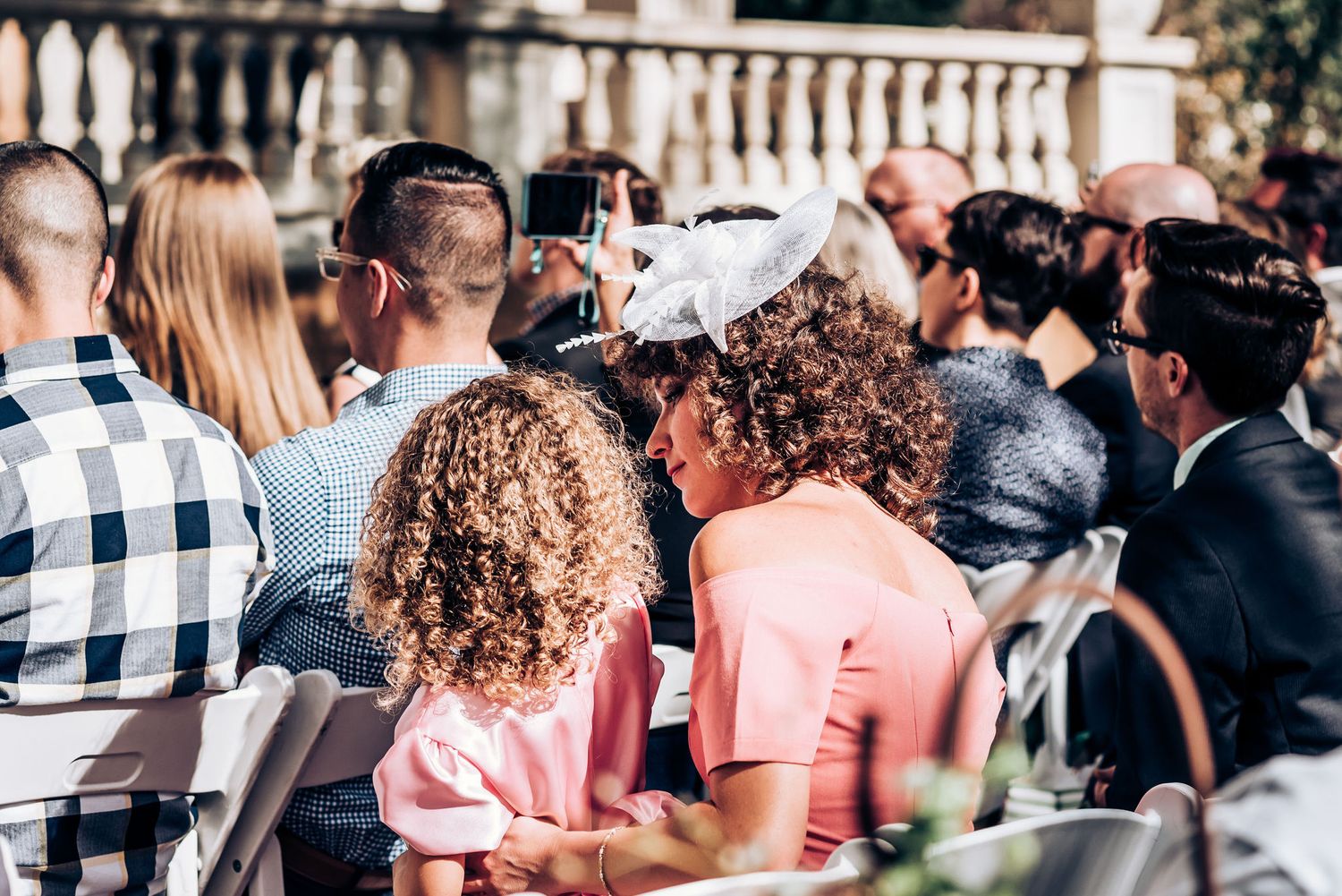Wedding guests seated outdoors watching the ceremony proceedings.