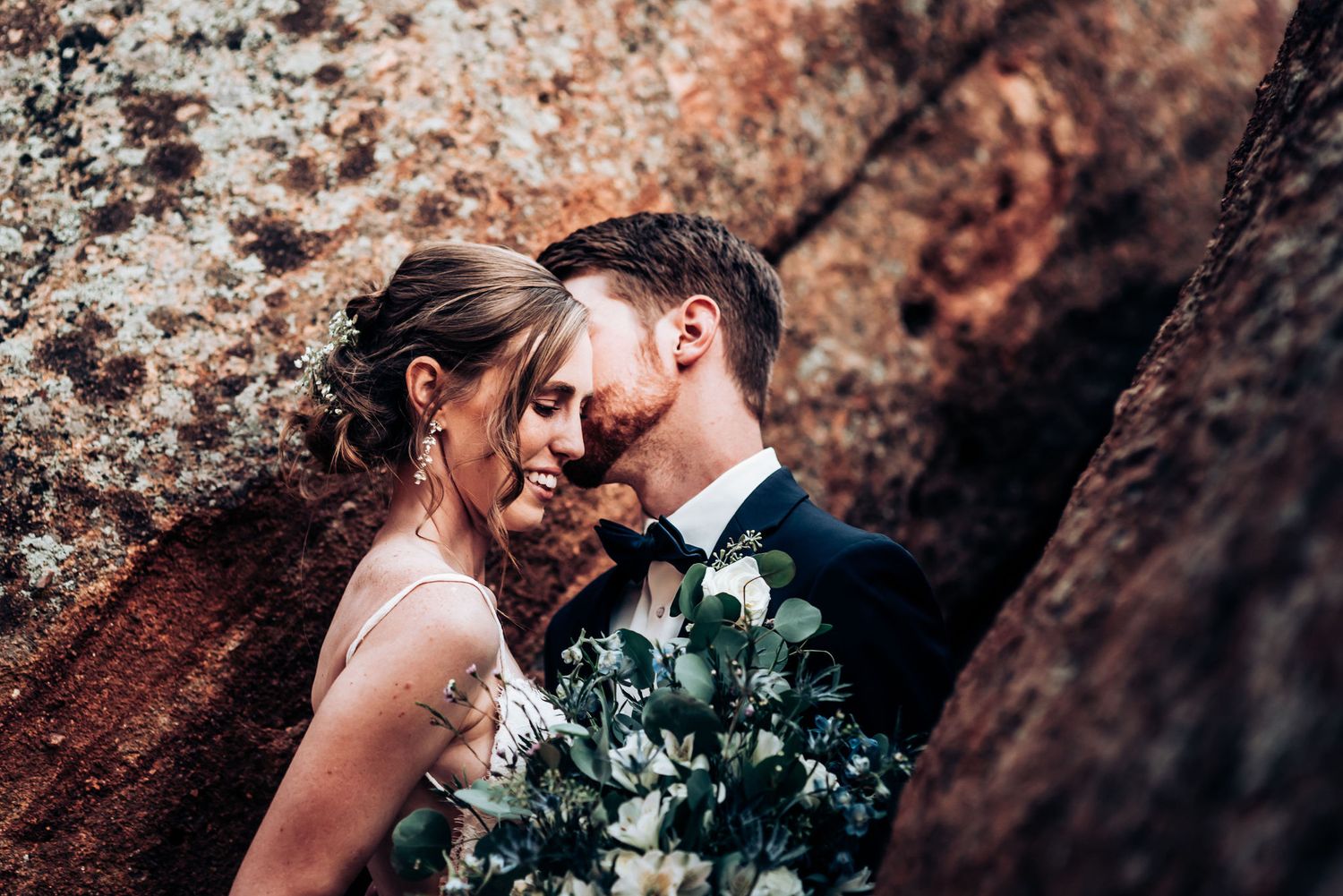 Intimate wedding moment against textured red rock formations.