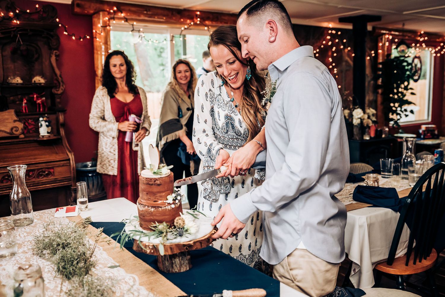 A small gathering celebrating around a decorated table with holiday lights and decor.