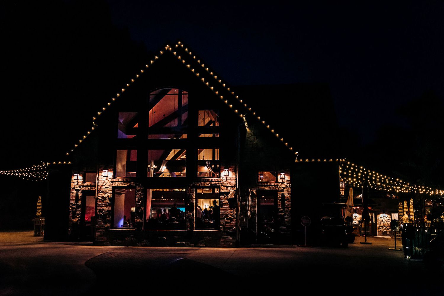 A festively lit lodge-style building glows at night with string lights.