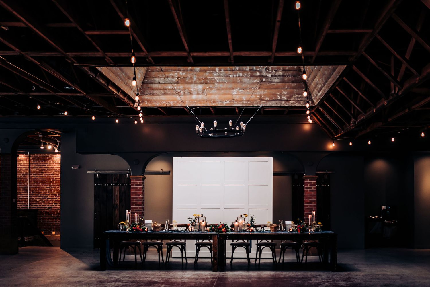 Modern industrial wedding reception space with exposed brick walls and minimalist bar setup.