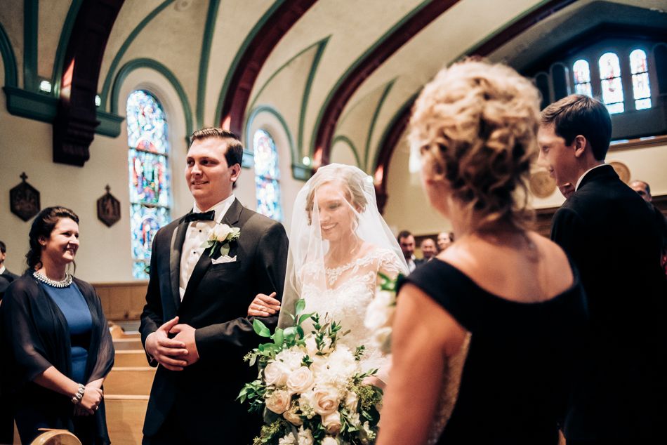 Wedding ceremony captured inside historic church with stained glass windows and arched ceilings.