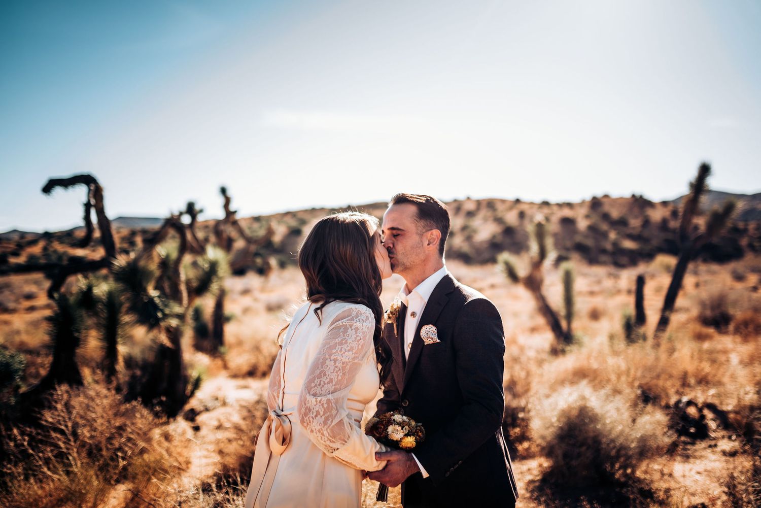 Intimate desert wedding moment captured against a backdrop of saguaro cacti and mountains.