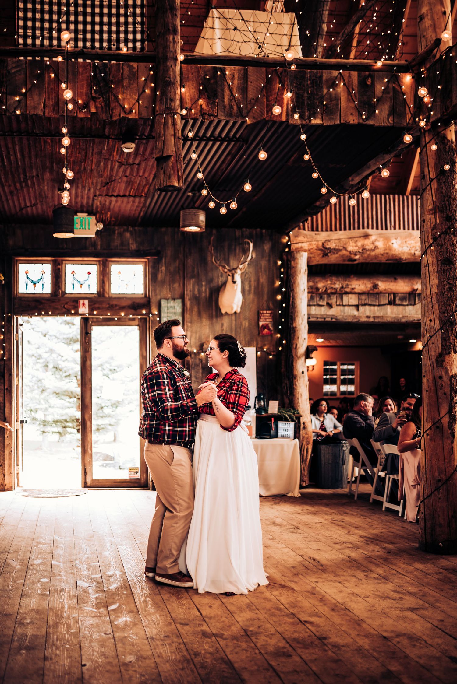 A couple shares their first dance in a rustic barn venue decorated with string lights.