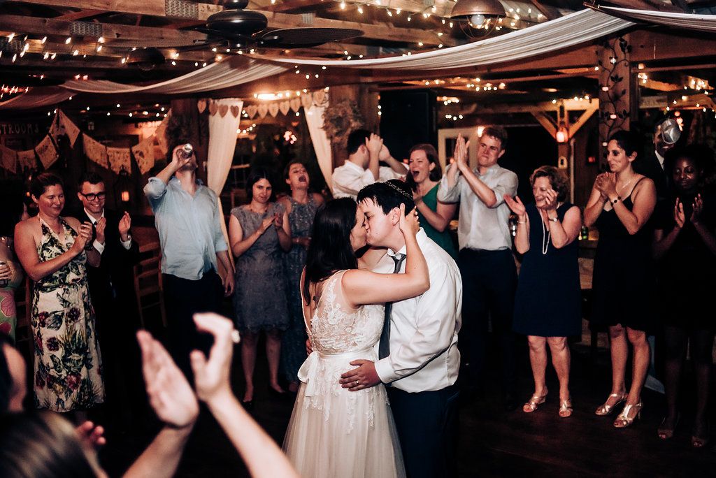 Wedding reception crowd cheers as couple shares a romantic dance under twinkling lights.