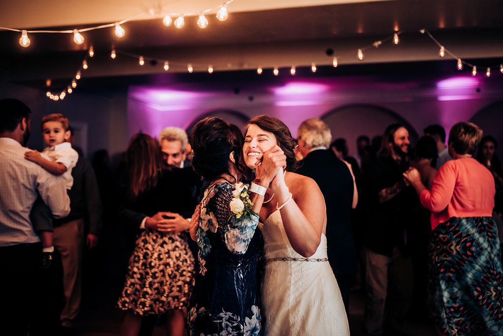 Wedding reception guests enjoying themselves on a lively dance floor with pink ambient lighting.