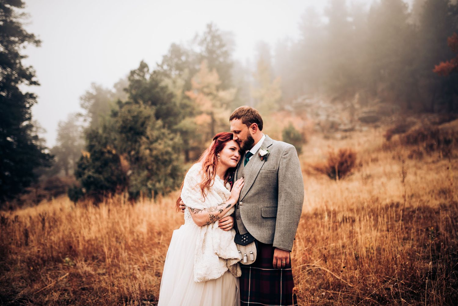 Scottish themed wedding photo with couple embracing in autumn mountain setting.