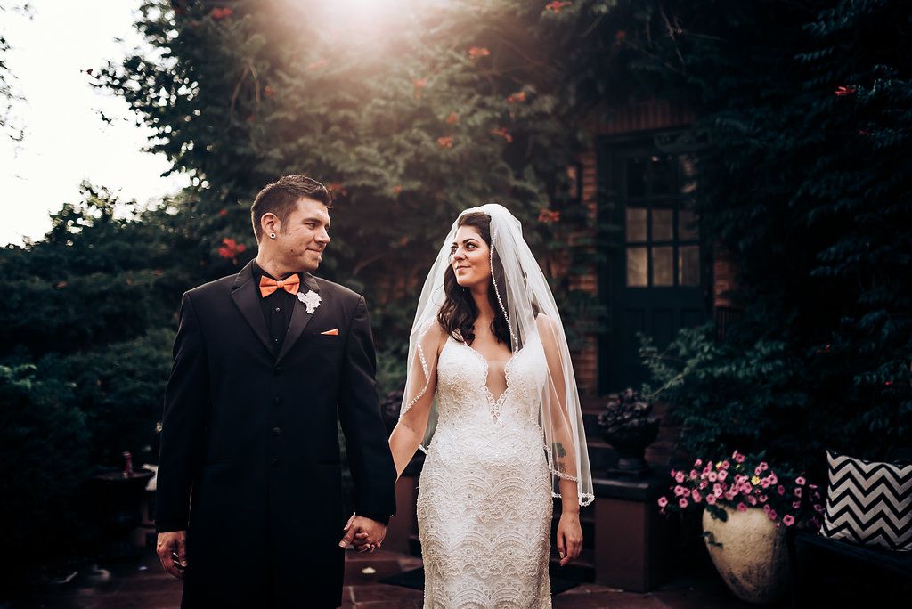 Sunset wedding portrait with couple holding hands against a backdrop of trees and natural light.