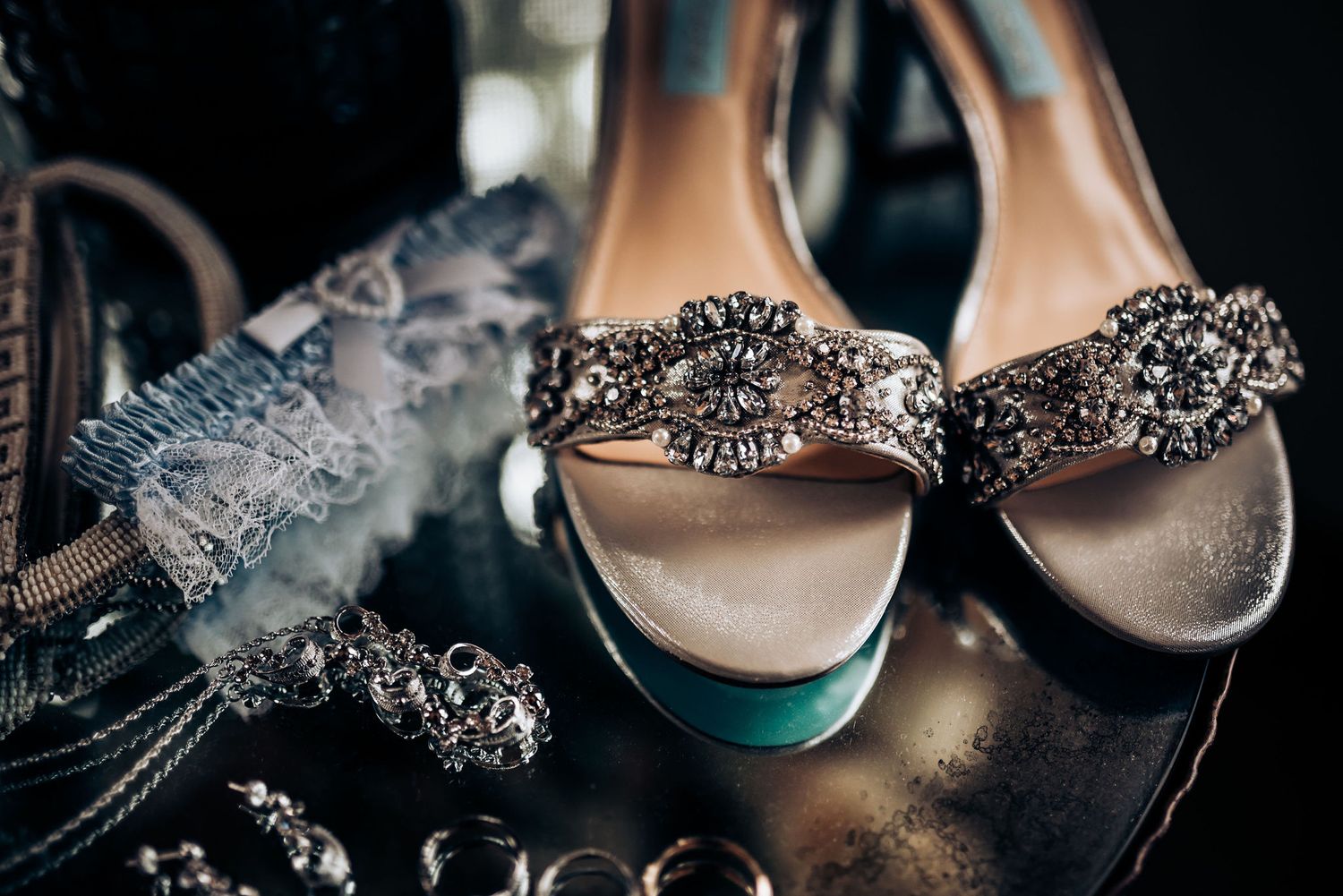 Crystal embellished bridal shoes with ornate beading displayed with jewelry.