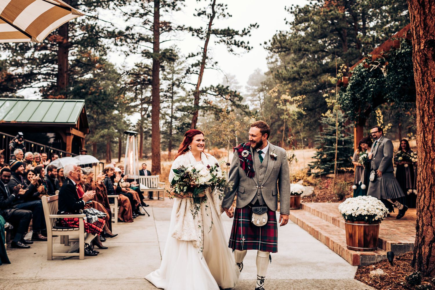 Scottish-themed wedding recessional with couple walking down aisle lined with white floral arrangements.