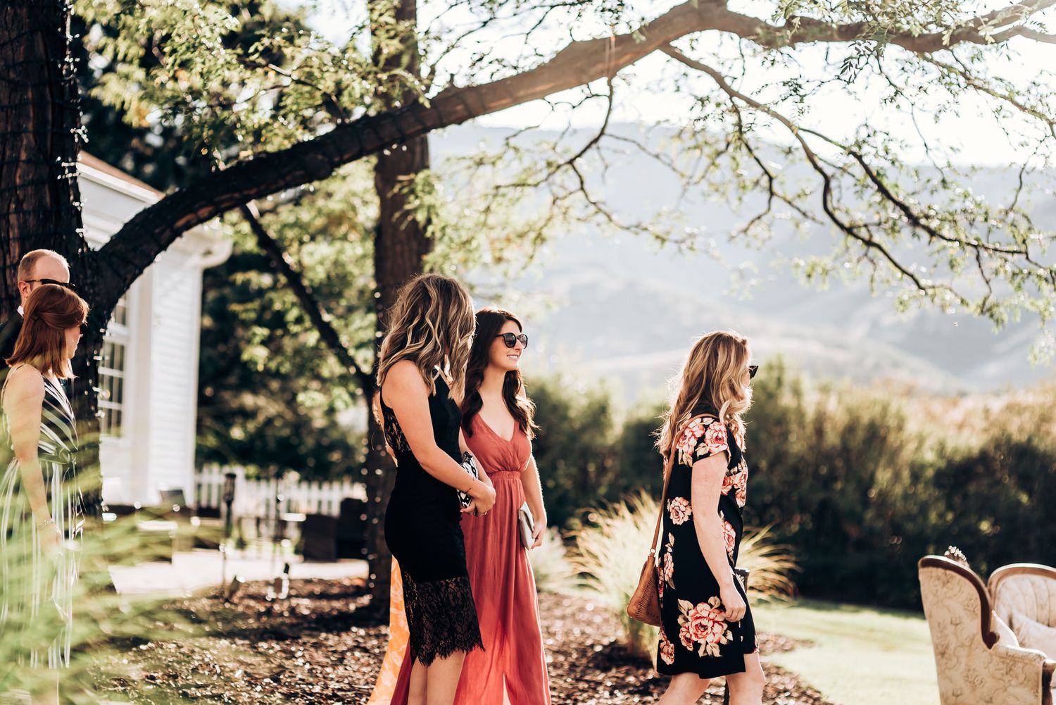Wedding guests in colorful dresses enjoying an outdoor ceremony with mountain views.