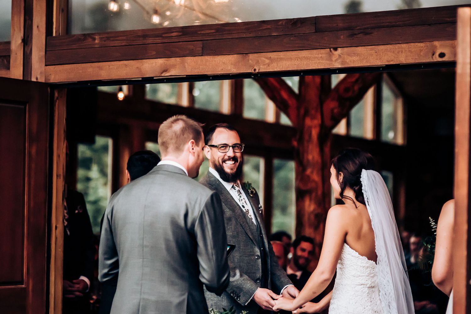Wedding ceremony taking place in a wooden-framed venue with natural lighting.