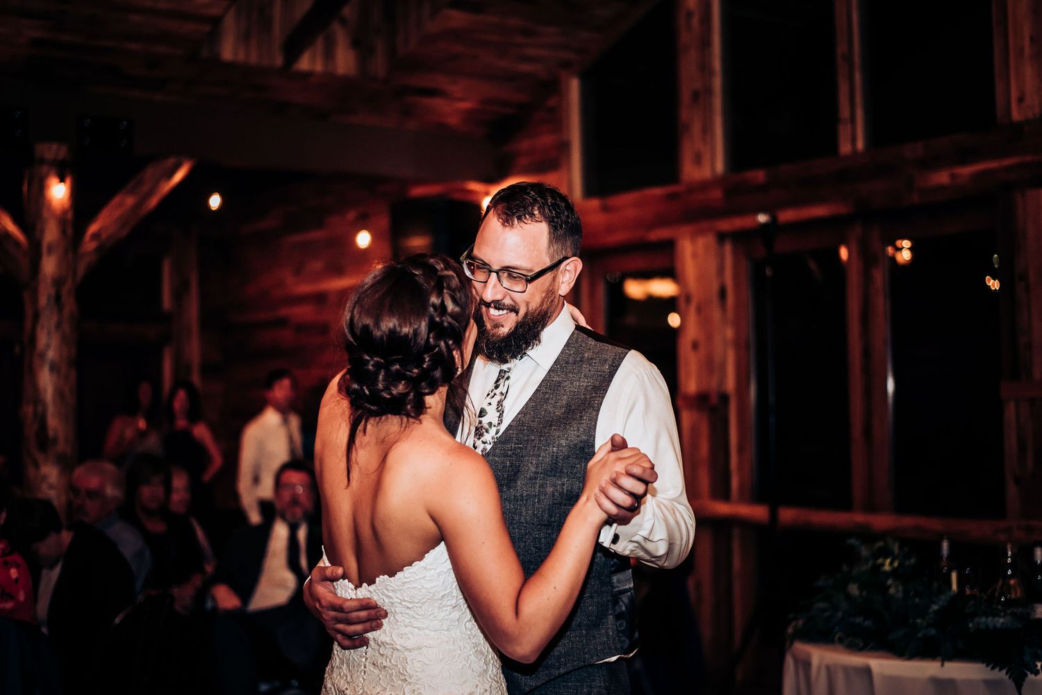 Couple shares an intimate dance moment in a rustic barn reception venue with wooden walls.