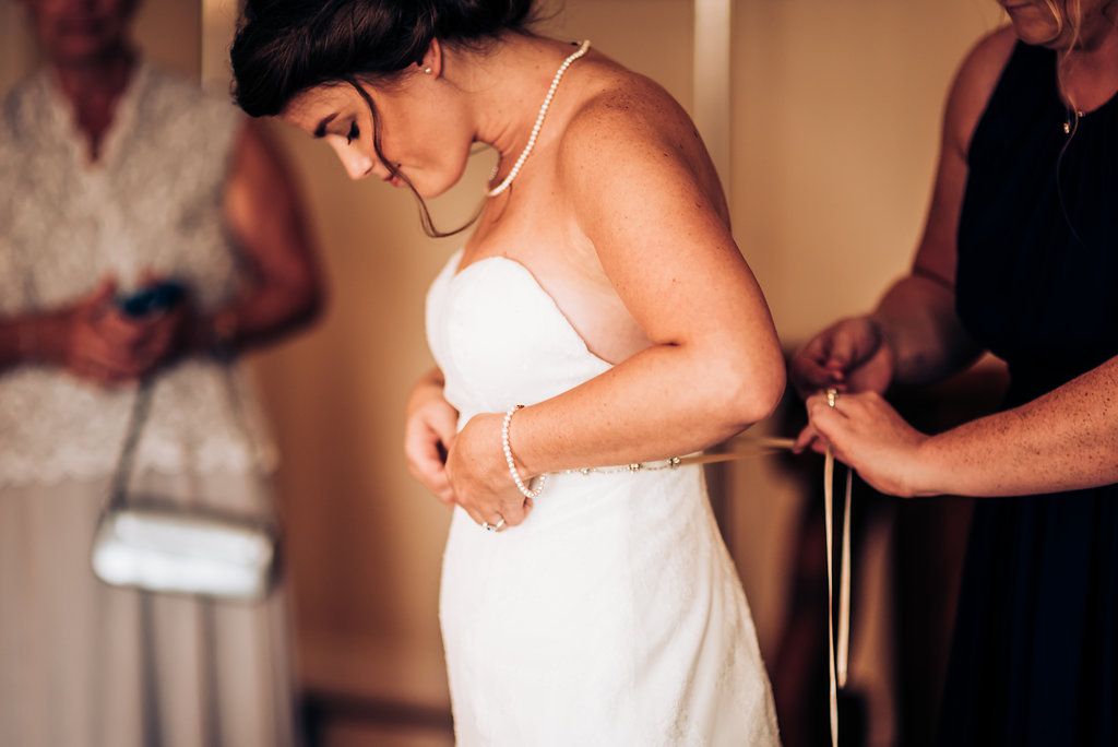 A woman in a white dress being fitted and adjusted.