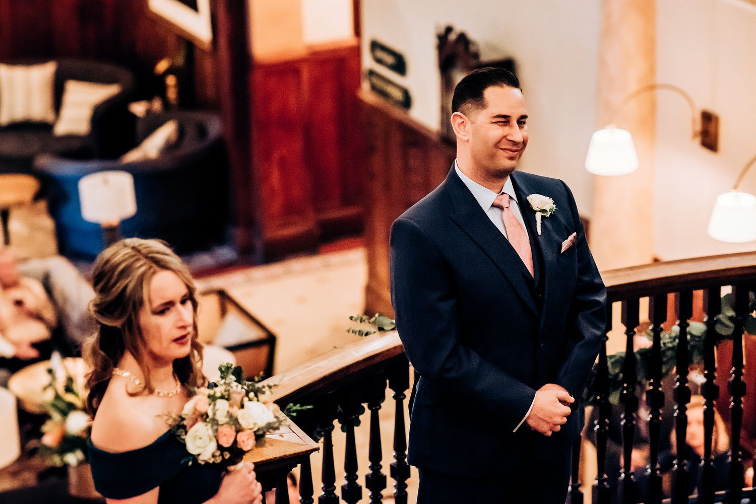 A formal celebration moment captured on an elegant wooden staircase with warm lighting.