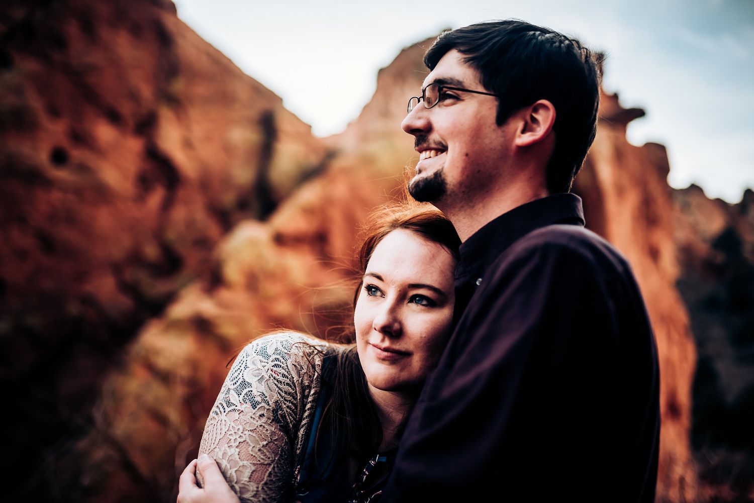 Intimate moment between couple with red rock formations in background.