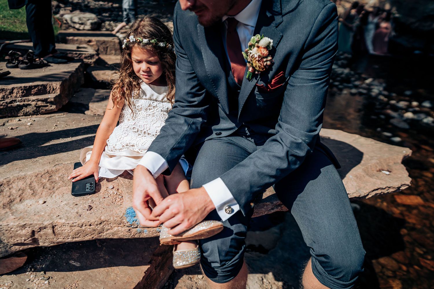 Close-up of wedding details near rocky riverside setting.