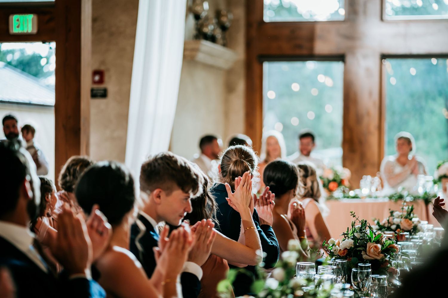 Wedding guests emotionally covering their faces during an intimate indoor reception moment.