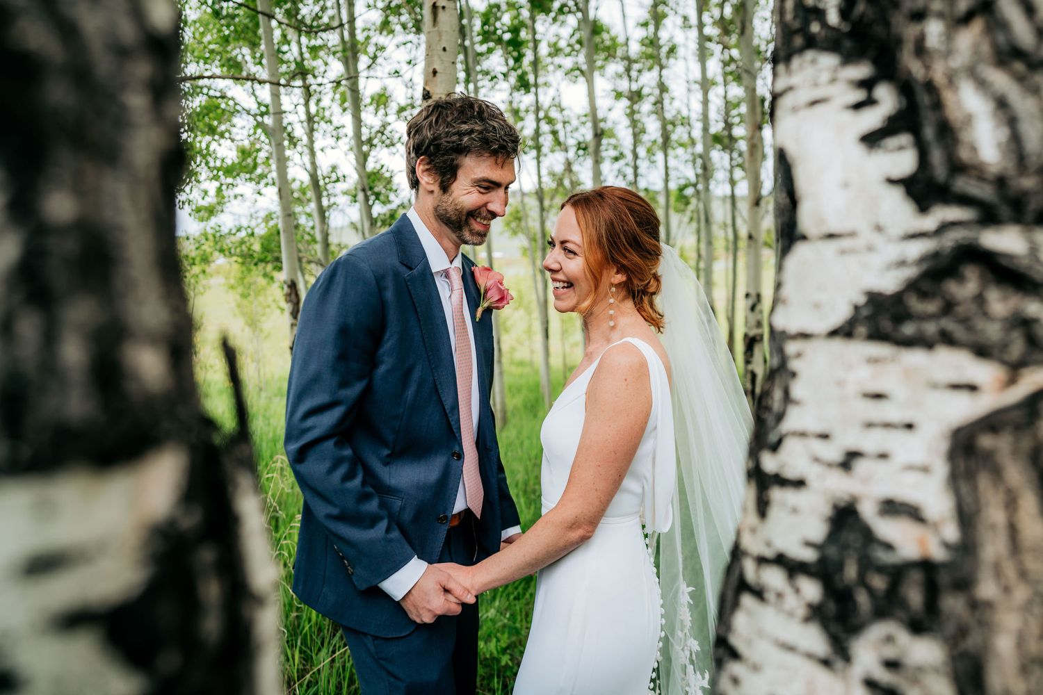 Wedding couple shares intimate moment among white birch trees in mountain setting.