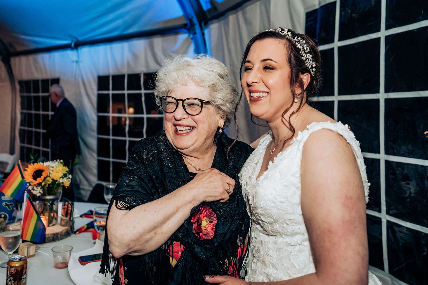 A joyful moment shared between two guests at a wedding reception under blue lighting.