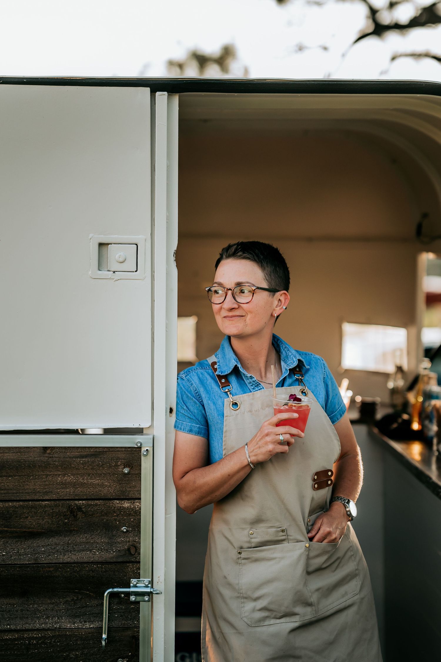 Server in blue shirt and apron preparing drinks behind a counter.