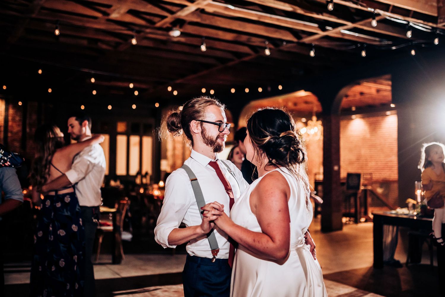 Couple shares an intimate slow dance at their wedding reception in an industrial-chic venue.
