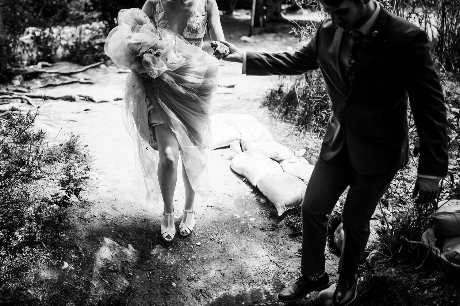 Black and white photo of couple dancing playfully outdoors during wedding celebration.
