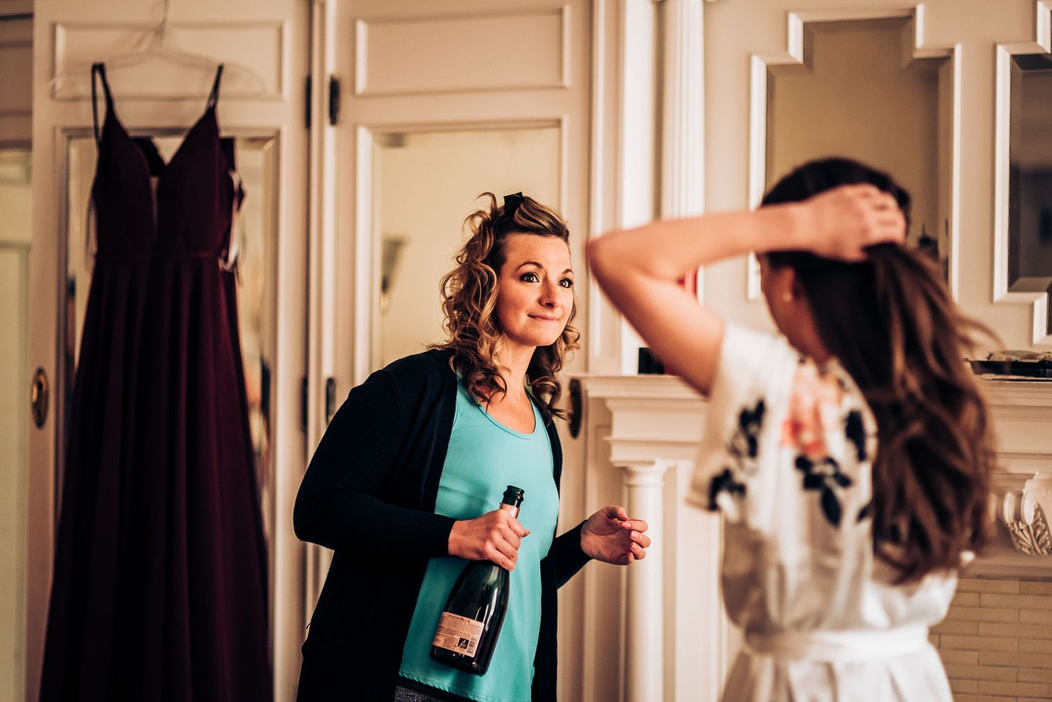 Woman in turquoise cardigan holds champagne bottle while preparing for special occasion.