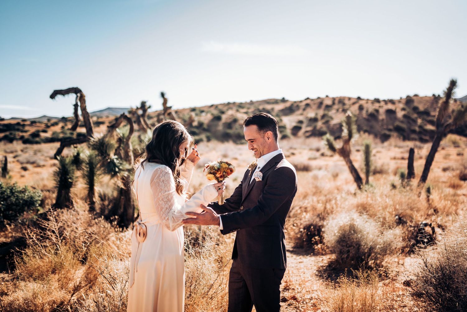 Wedding ceremony in a scenic desert setting with towering cacti and golden light.