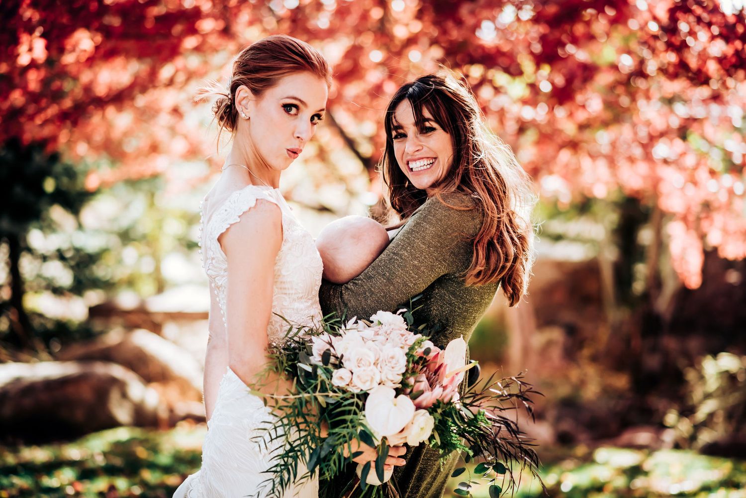 Autumn wedding portrait with white floral bouquet against red maple leaves.