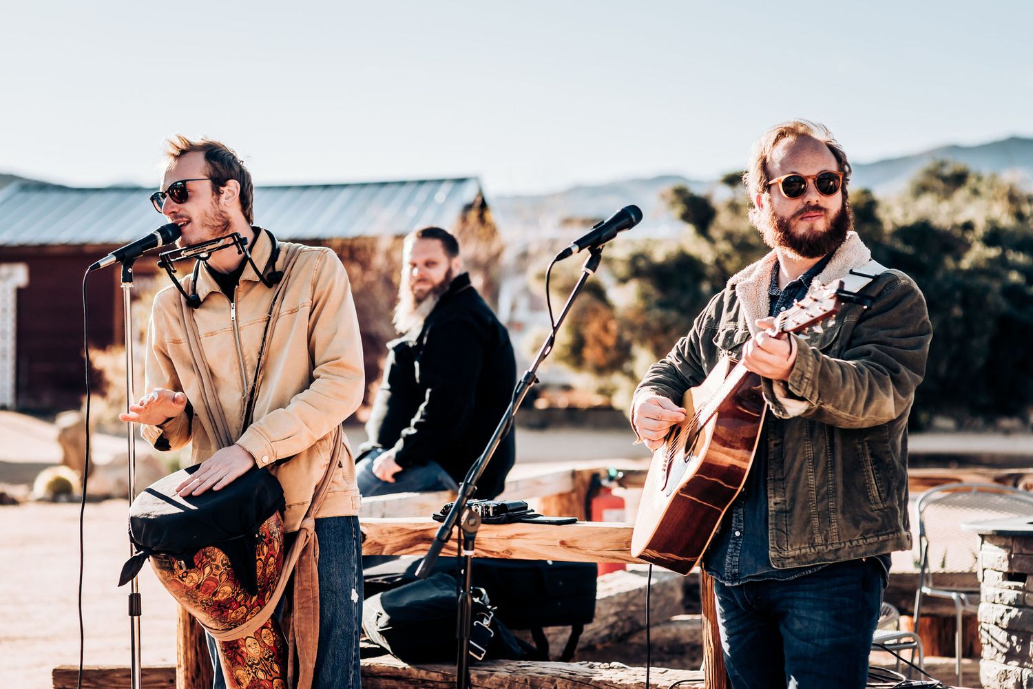Musicians perform at an outdoor desert wedding with instruments and microphones.
