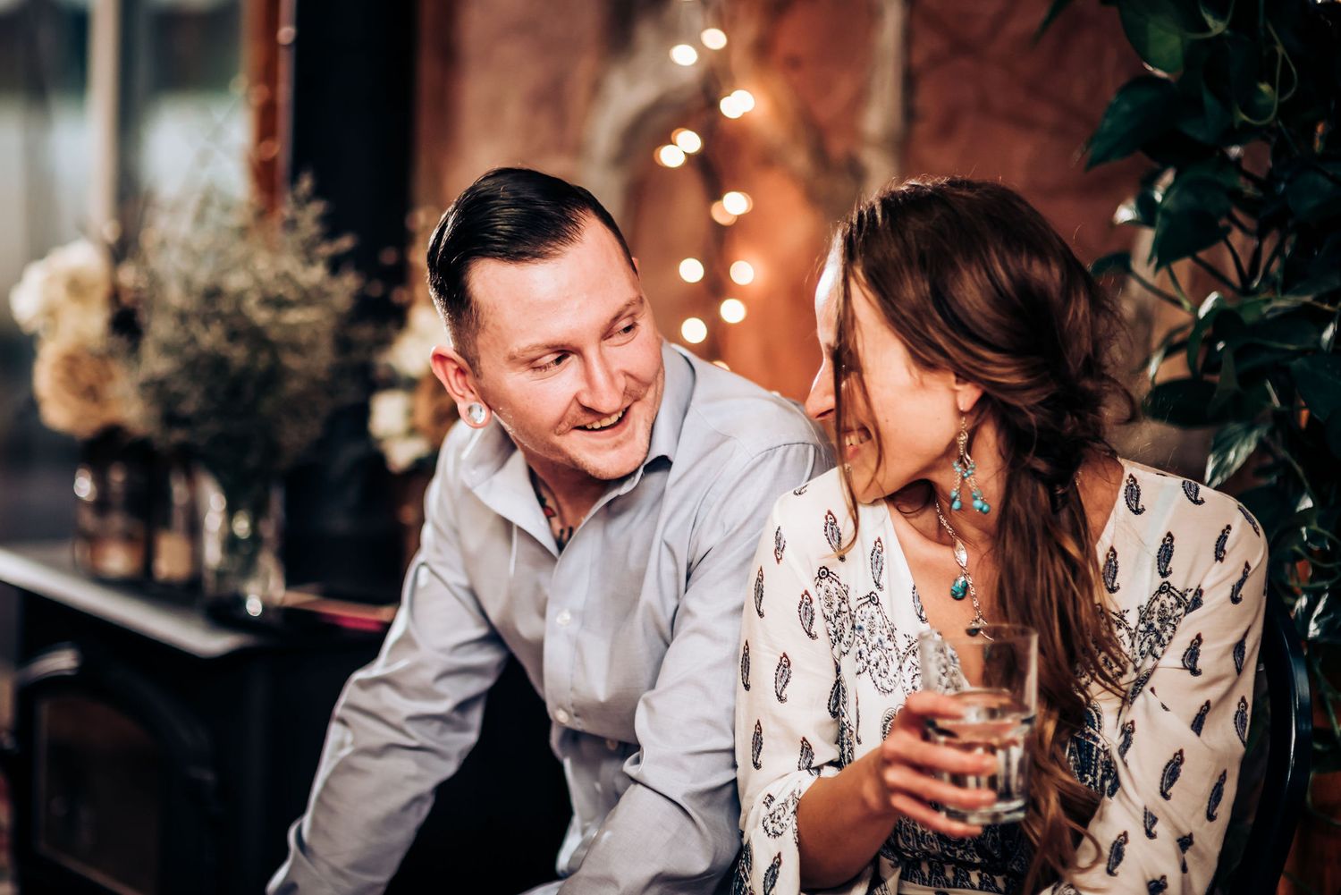 A couple shares an intimate moment while enjoying drinks in a romantically lit setting.