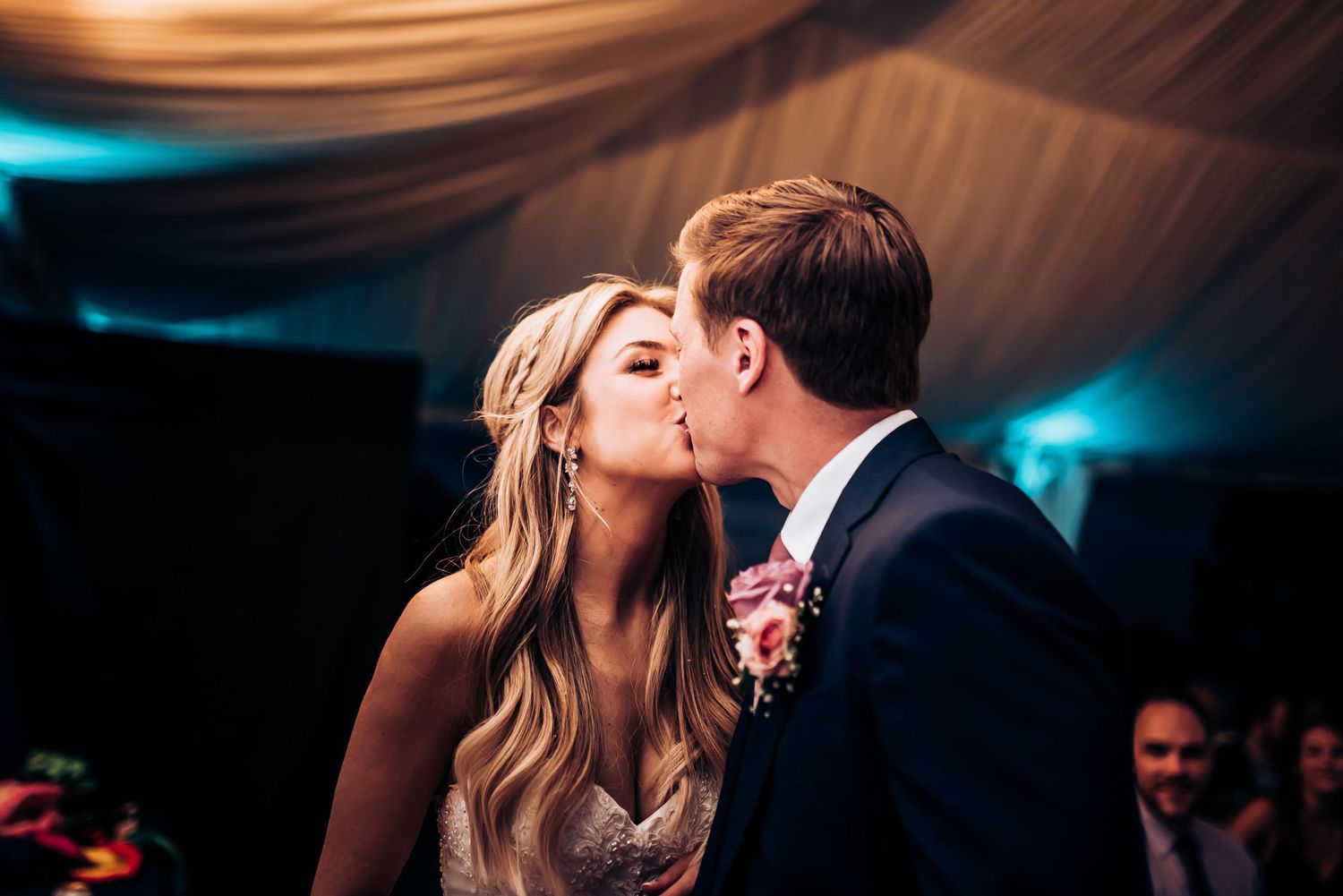 Intimate wedding moment captured during the cake cutting tradition at an evening reception.
