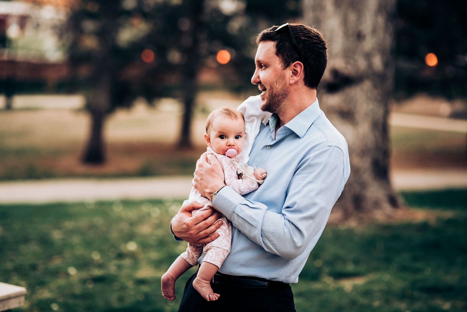 A sweet moment captured outdoors in a park setting on a warm day.