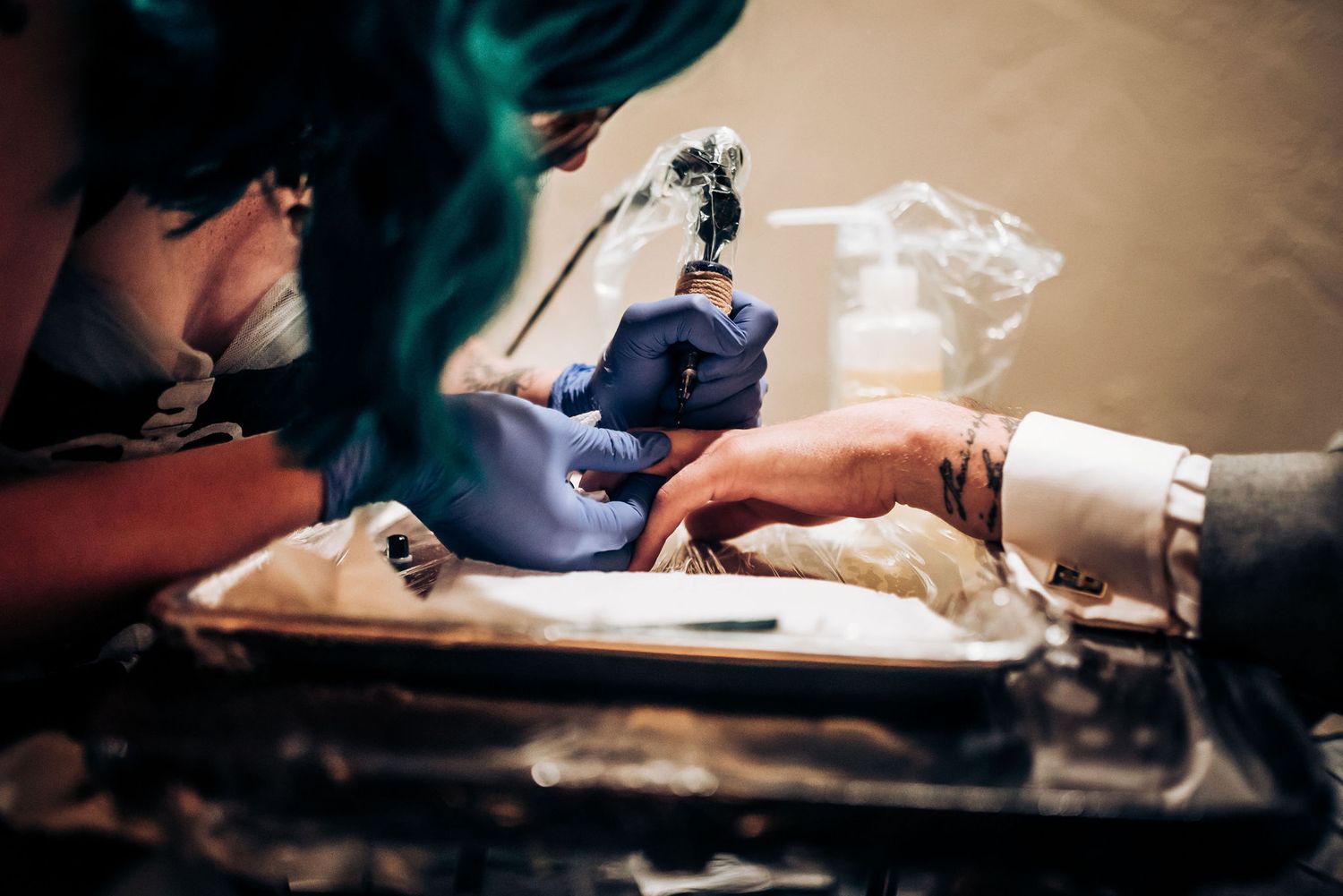Close-up of hands using tattoo machine during wedding ceremony.