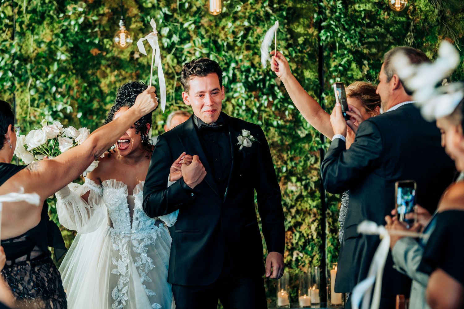 Celebratory moment during wedding ceremony with guests raising white ribbons.