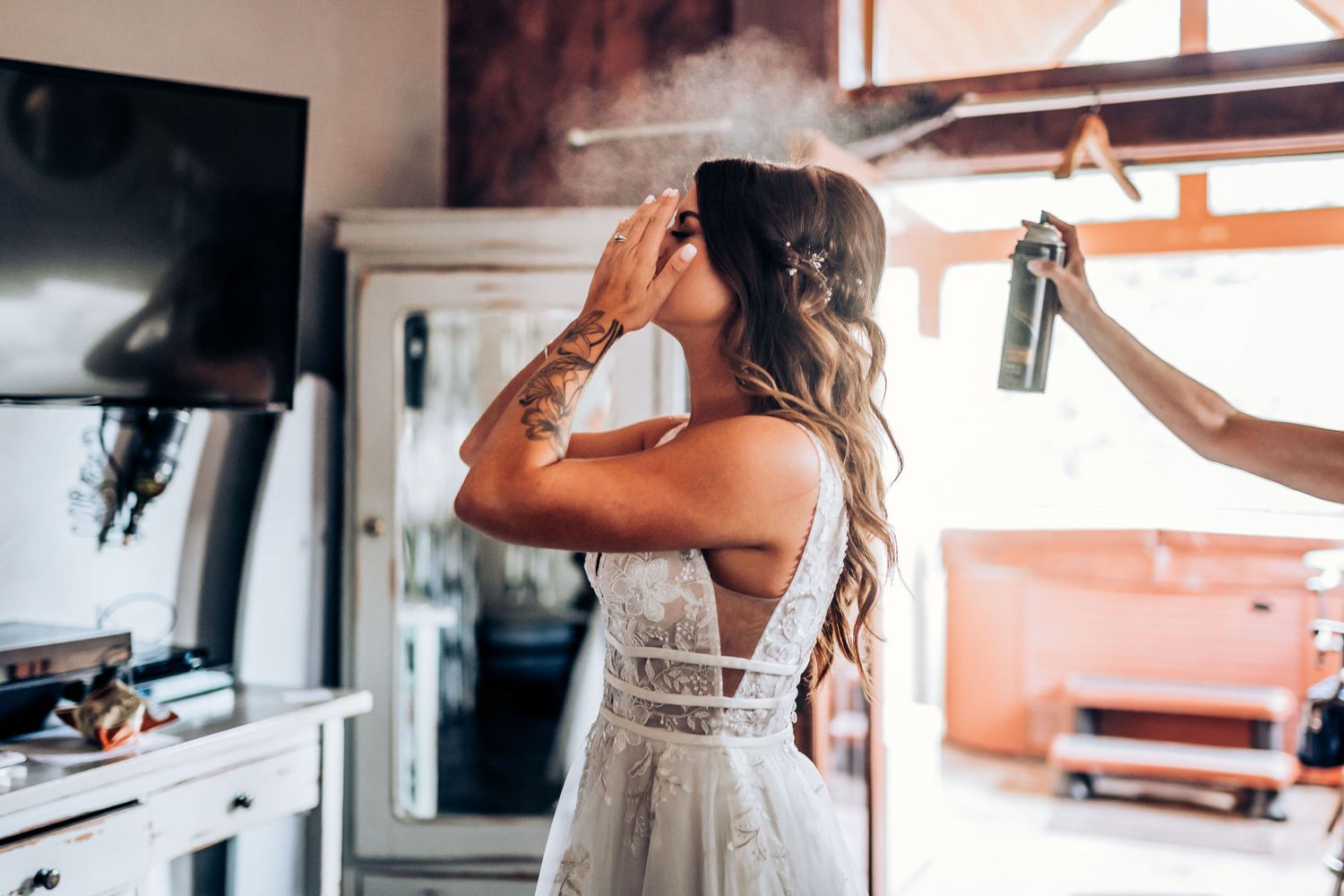 Behind-the-scenes moment of wedding preparation with white dress being adjusted.