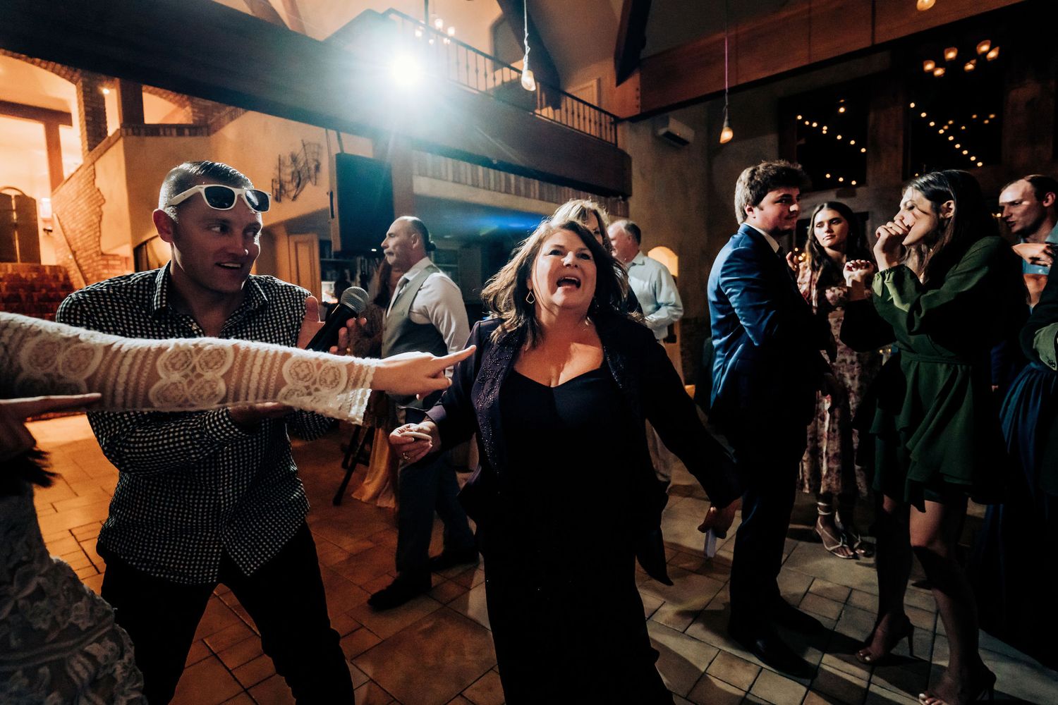 Party guests dancing energetically under indoor venue lighting at celebration event.